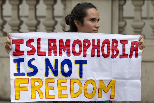 A protester holds a sign which reads " Islamophobia is not freedom" outside the French Embassy in London on August 25, 2016 during a "Wear what you want beach party" to demonstrate against the ban on Burkinis on French beaches and to show solidarity with Muslim women. French Interior Minister Bernard Cazeneuve warned Wednesday against stigmatising Muslims, as a furore over the banning of burkinis grew with the emergence of pictures showing police surrounding a veiled woman on a beach.  Dozens of French towns and villages, mostly on the Cote d'Azur, have banned beachwear that "conspicuously" shows a person's religion -- a measure aimed at the full-body Islamic swimsuit but which has also been used against women wearing long clothes and a headscarf. / AFP PHOTO / JUSTIN TALLIS